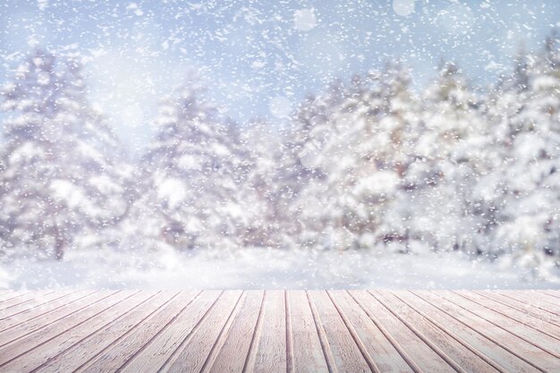 Photo view on a brown wooden table against a winter forest in blur and snowfall background abstract concept copy space