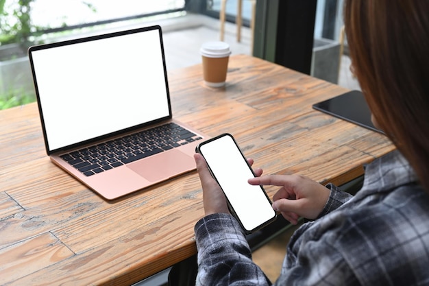 View over businesswoman shoulder sitting in office and using mobile phone