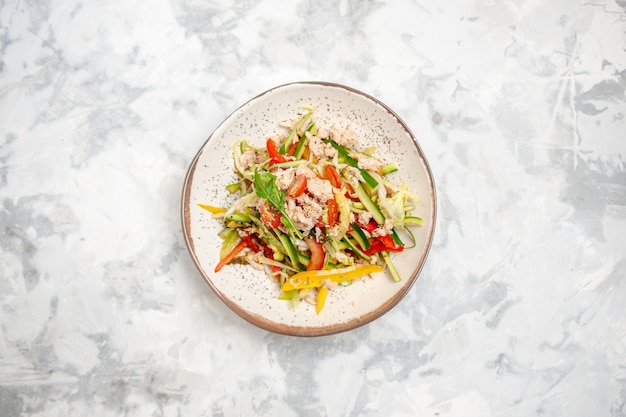 Above view of chicken salad with vegetables on stained white surface with free space