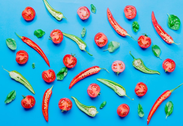 Above view at Chili pepper and tomatoes with basil on blue background