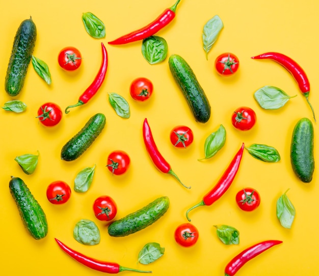 Above view at Chili pepper and tomatoes with cucumbers on yellow background