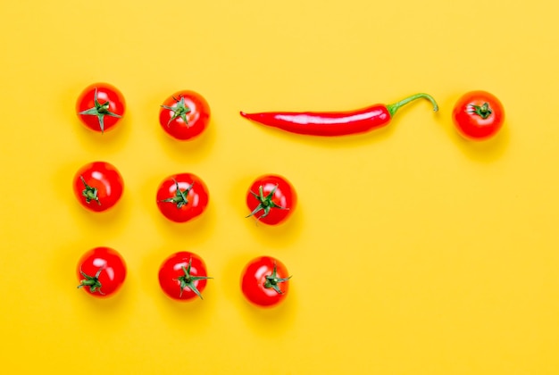 Above view at Chili pepper and tomatoes on yellow background