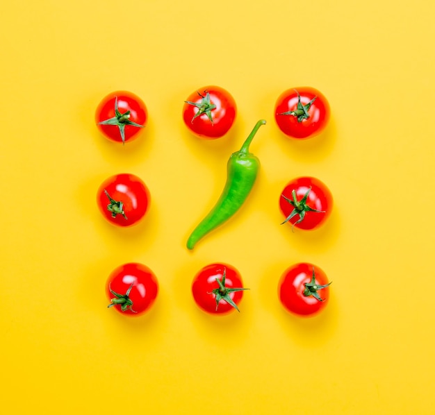 Above view at Chili pepper and tomatoes on yellow background