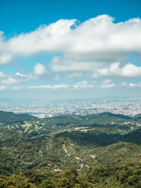 View of city from the beautiful mountain. Blue sky and green meadow in sunset time.