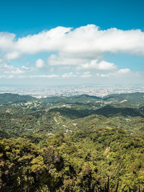 View of city from the beautiful mountain. Blue sky and green meadow in sunset time.