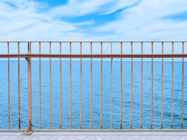 View on a clear blue sea under the cloudy sky through a fencing of a breakwater