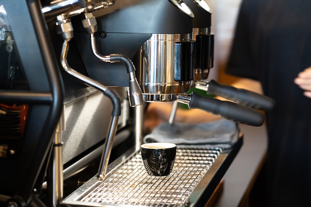 View of cup of coffee under coffee grinder.