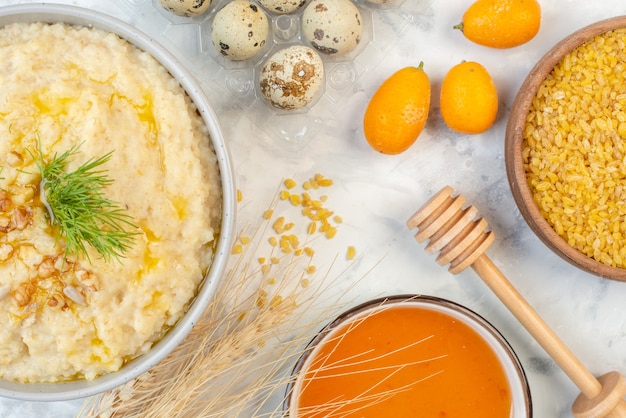 Above view of delicious breakfast with oats eggs brown rice spikes honey on ice background