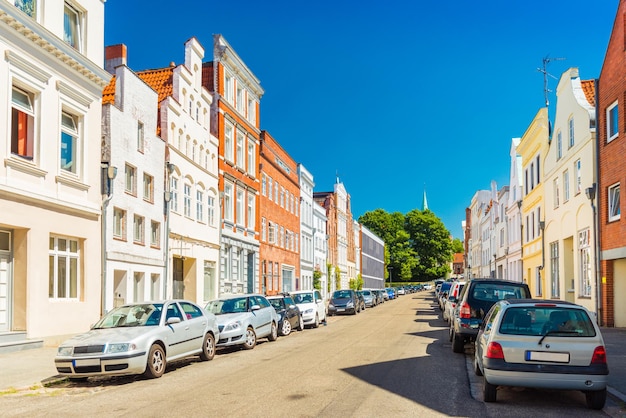 View of an empty street in Lubeck, Germany. Row of residential houses and cars parked along the street