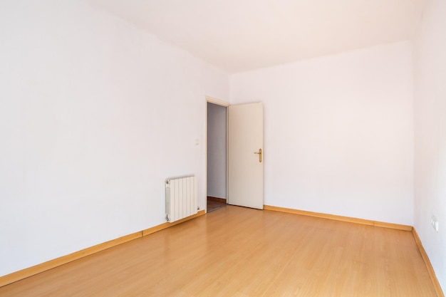 View of the entrance to an empty room painted white with the color of wood on the floor and a