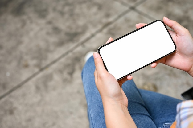 Above view A female using her smartphone to watch a movie while relaxing in the park