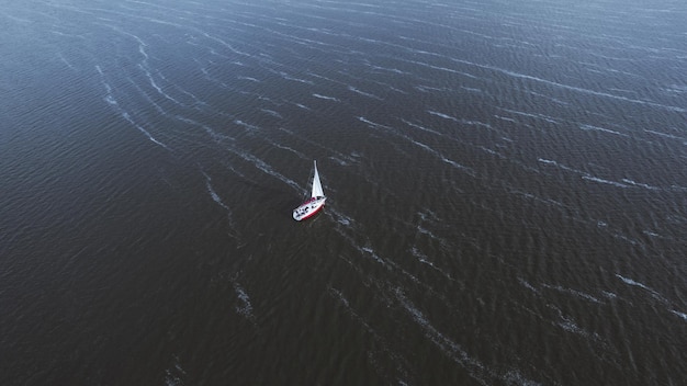 View from above aerial view of sailing white modern not big sail boat or yacht with sail