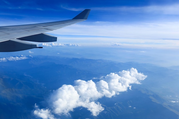 View from airliner window with white clouds and mountain range