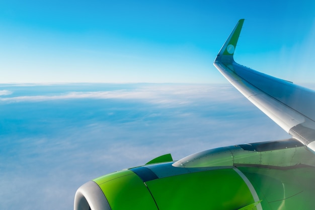 view from the airplane window wing and turbine of an airplane on a background of blue sky