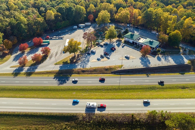 View from above of big parking rest area for cars and trucks near busy american highway with fast moving traffic Recreational place during interstate travel