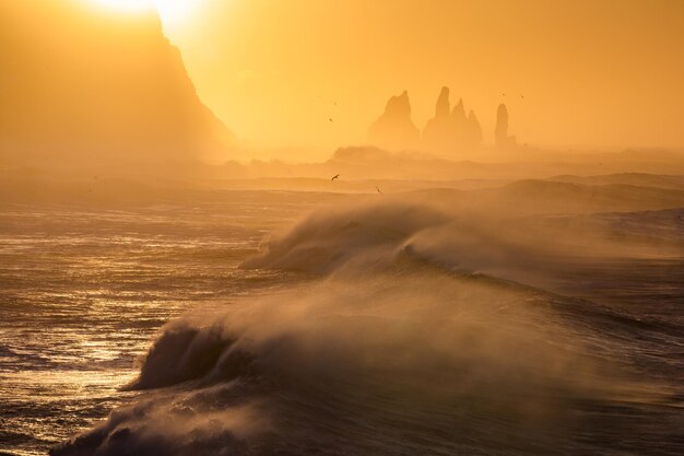 View from cape Dyrholaey on Reynisfjara Beach and Reynisdrangar basalt sea stacks Iceland Stormy sunrise