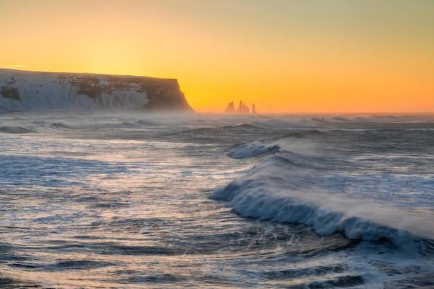 View from cape Dyrholaey on Reynisfjara Beach and Reynisdrangar basalt sea stacks Iceland Stormy sunrise