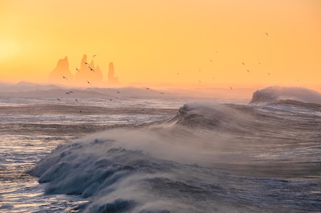 View from cape Dyrholaey on Reynisfjara Beach and Reynisdrangar basalt sea stacks Iceland Stormy sunrise