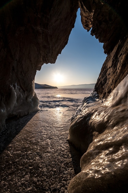 View from the cave to winter Lake Baikal with ice in sunny weather