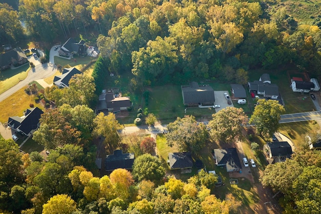 View from above of expensive residential houses between yellow fall trees in suburban area in South Carolina American dream homes as example of real estate development in US suburbs