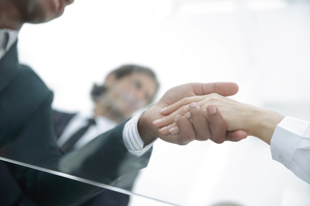 View from below. From behind the glass. Handshake of business partners