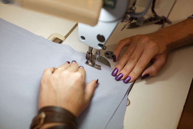 View from above on hands of female tailor working on sewing machine