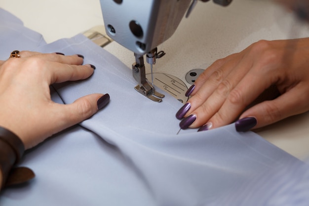 View from above on hands of female tailor working on sewing machine