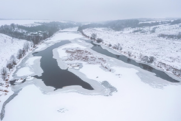 View from a height of a frozen river covered with snow Cold winter Beautiful ice patterns on the river from above