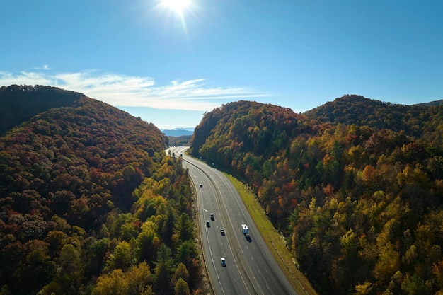 View from above of I40 freeway route in North Carolina leading to Asheville thru Appalachian mountains with yellow fall woods and fast moving trucks and cars Interstate transportation concept