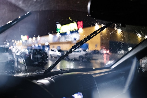 A view from inside the car of the windscreen wiper cleaning during night heavy rain