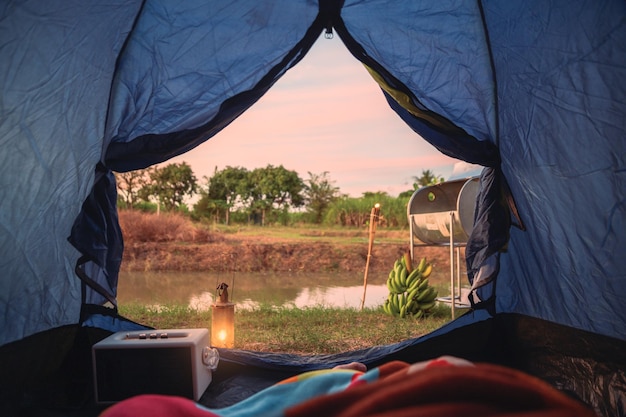 View from inside of tent with relaxing and campfire near swamp