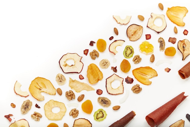 View from above of neatly stacked fruit lozenge different colors and almonds, orange, dried apricot, raisins, walnuts, dried apples and kiwi on white