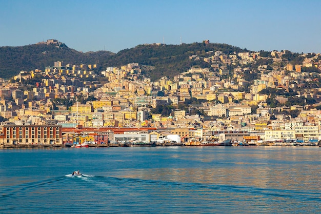 View from the sea to Italian city of Genoa with houses on coast yachts and ships moored at pier