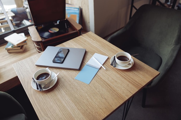 View from above on table with two white cups of coffee and business stuff laptop and phone