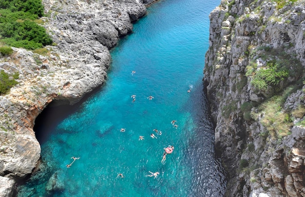 View from above on the turquoise water and swimmers in a bay of the Adriatic in Puglia bordered by cliffs