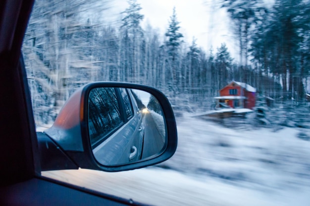 The view from the window of the car  the rear view mirror and snowcovered forest