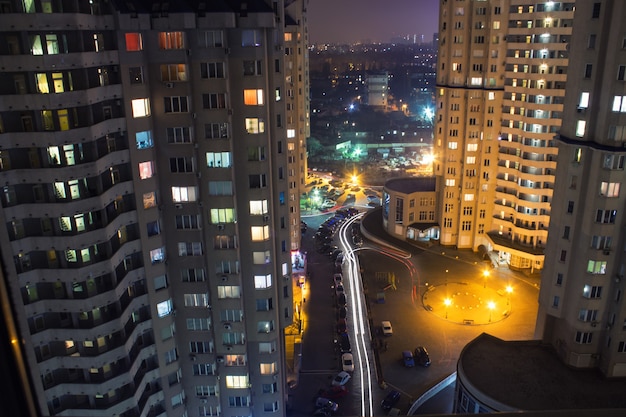 View from window high-rise buildings at night with illumination and moving cars with blur light