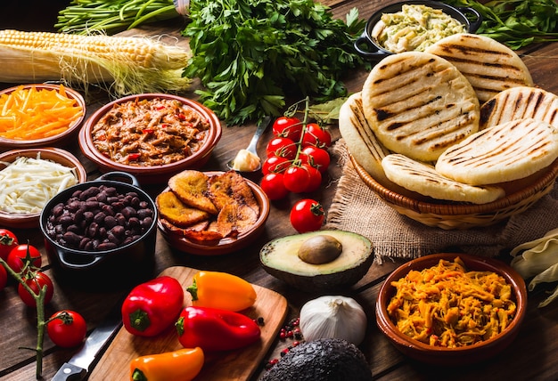 View from above of a wooden rustic table with several ingredients for cooking and filling arepas