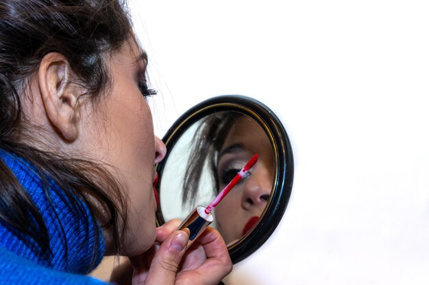 View of girl painting her lips and looking in the mirror at home Reflection of young woman in the mirror painting her lips