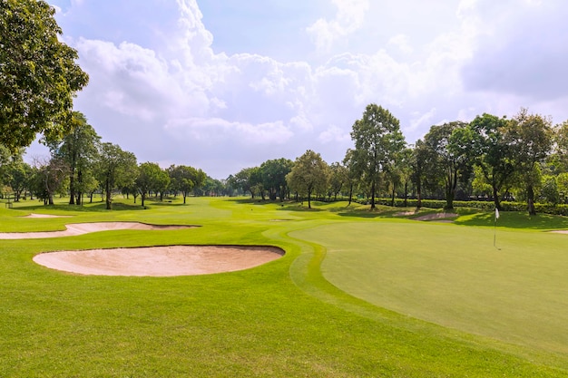 View of a golf course in Thailand with lush green grass beautiful scenery with sand pits bunker beside the greens and golf holes blue sky sunny day