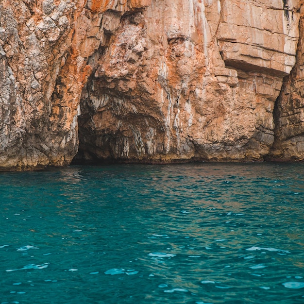 View of grotto in rocky cliff with azure water