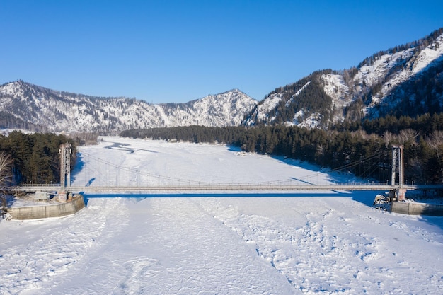 Above view of hanging bridge over Katun river against Altai mountains on background