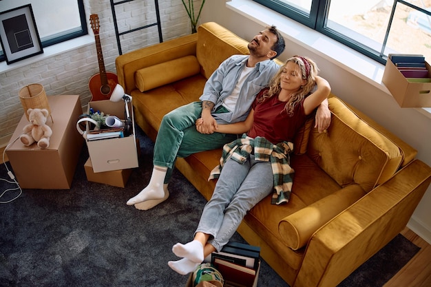 Photo above view of happy couple relaxing on the sofa in their new home