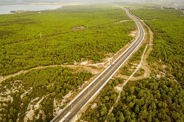 View of the highway car road through green forest from above travel adventure concept