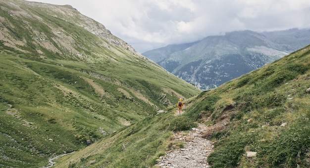 View of a hiker walking on a path between the mountains