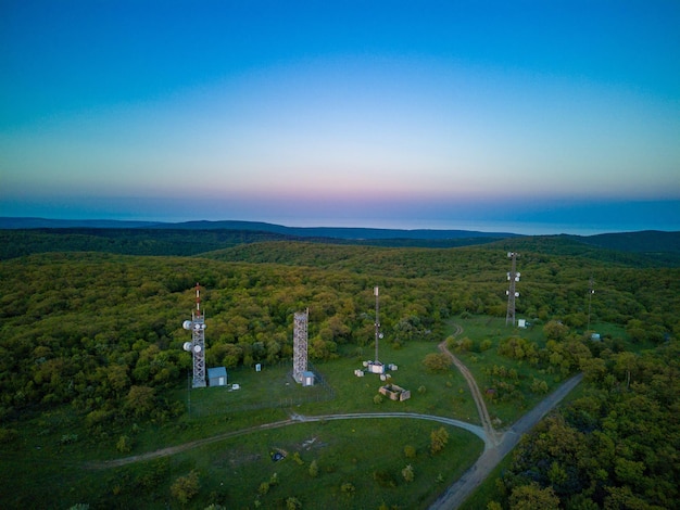 View of the hills covered with vegetation with cell towers against the backdrop of fields and a clear sky