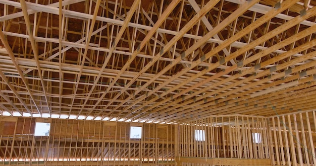 A view of the interior of a wooden building with a wooden truss and a wood beam framework under construction