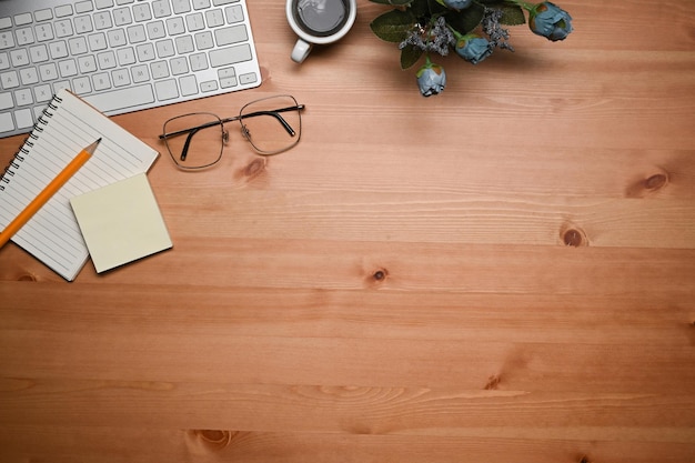 Above view keyboard glasses coffee cup and notebook on wooden table