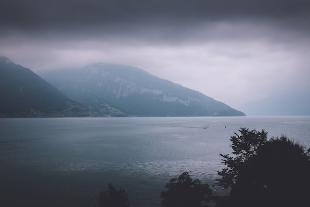 View on lake Thun and mountains from ship in city Spiez, Switzerland, Europe. Dramatic moody blue clouds scene