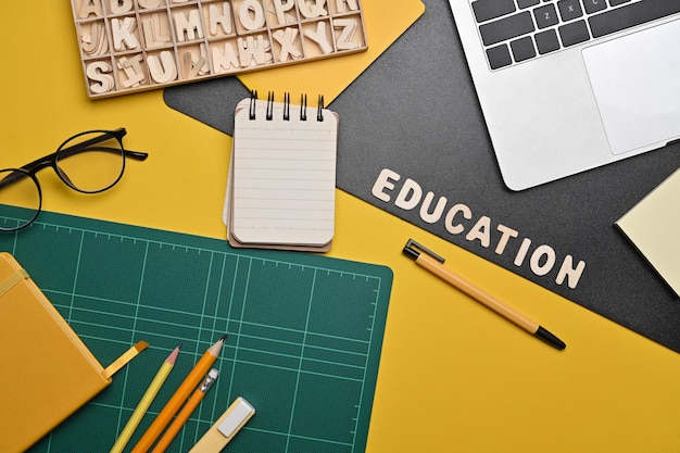 Above view laptop computer glasses and stationery on yellow background Back to school concept